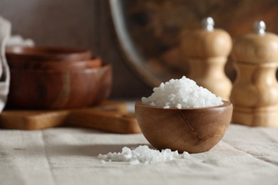 Photo of Organic salt in wooden bowl on table, closeup. Space for text