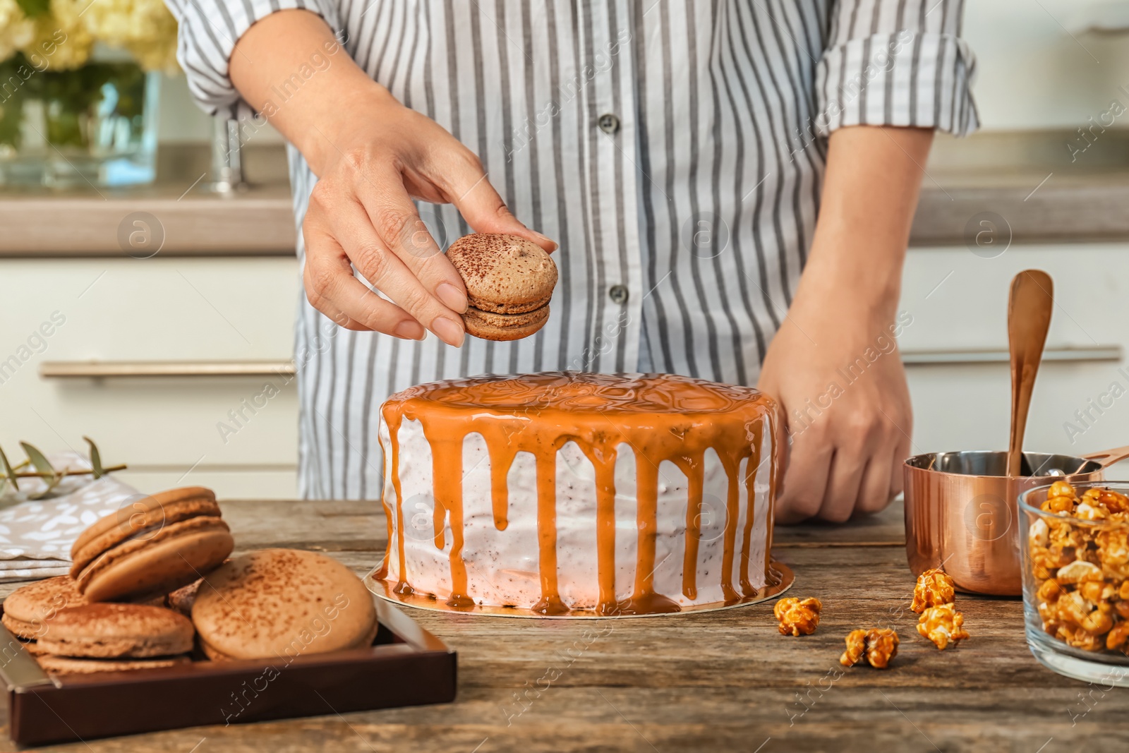 Photo of Young woman decorating delicious caramel cake at table