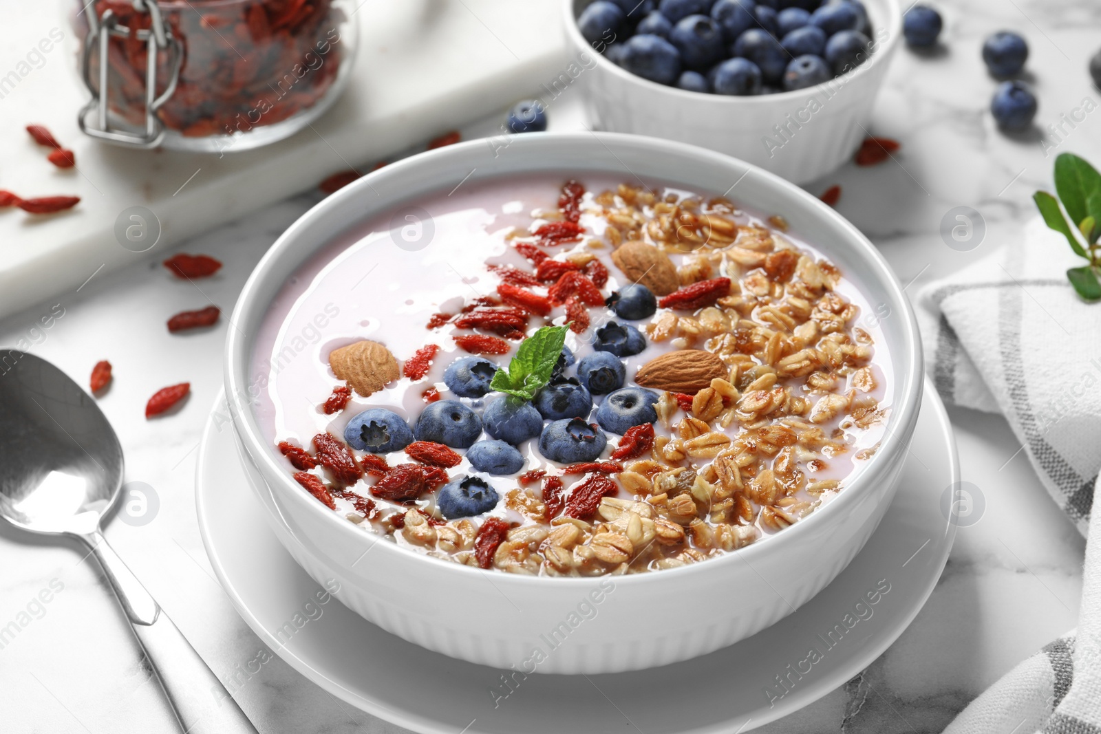 Photo of Smoothie bowl with goji berries and spoon on marble table