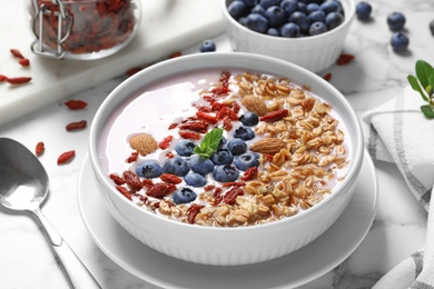 Smoothie bowl with goji berries and spoon on marble table