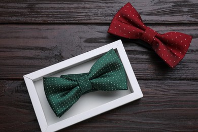 Different stylish bow ties on wooden table, flat lay