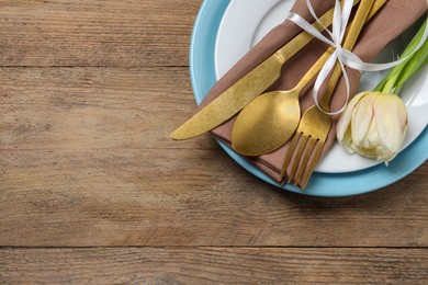 Photo of Stylish table setting with cutlery and tulip on wooden background, top view. Space for text