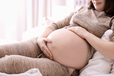 Photo of Young pregnant woman lying on bed at home