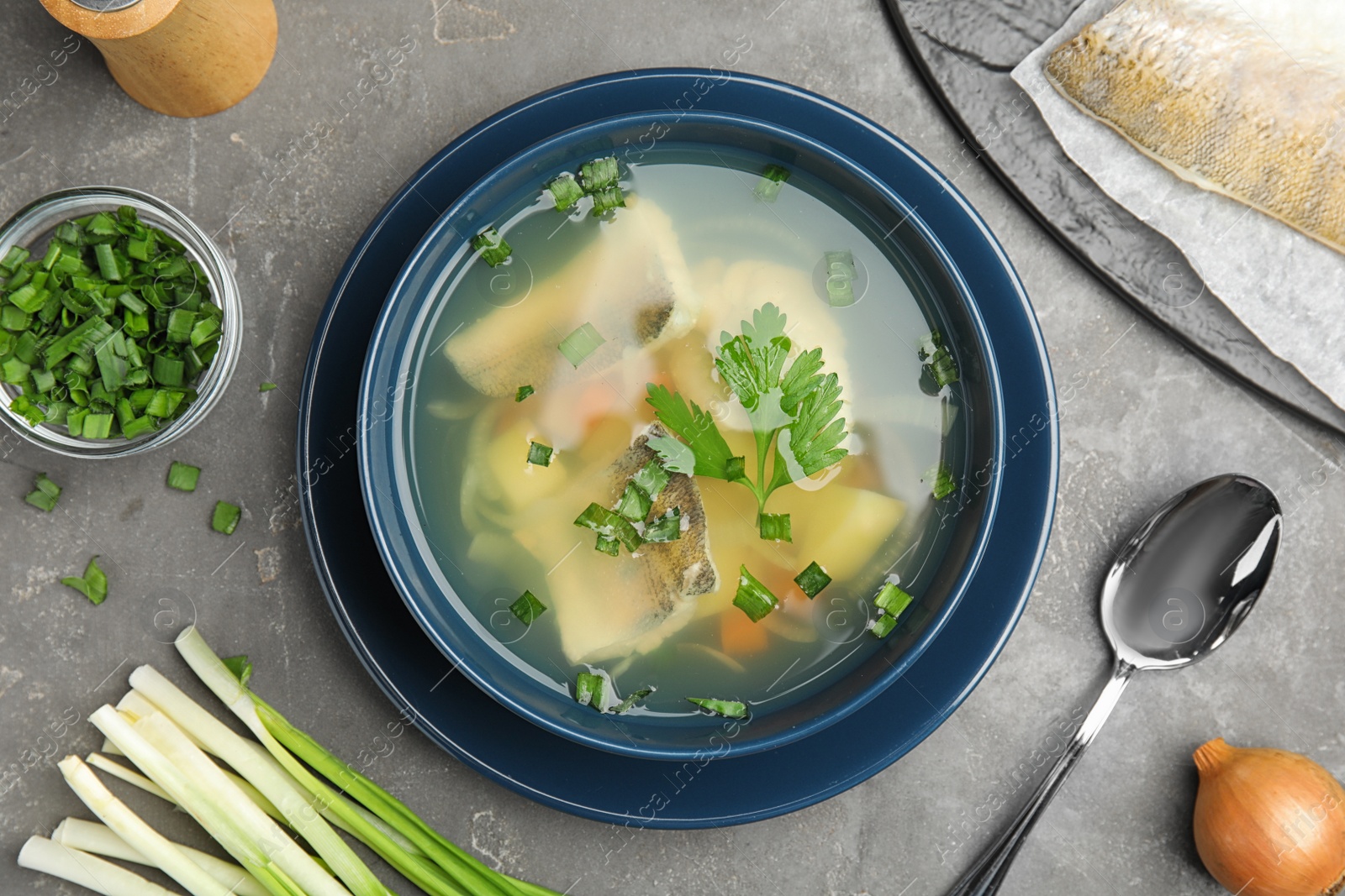 Photo of Flat lay composition with delicious fish soup on grey table