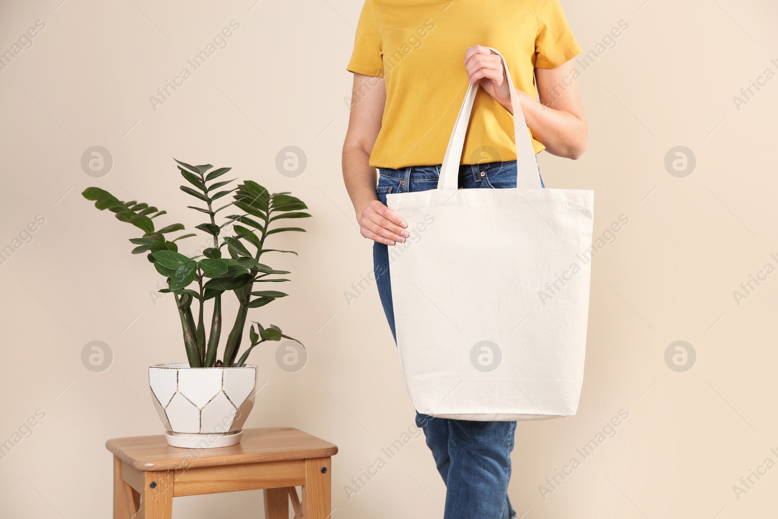 Photo of Woman with eco bag near green plant on color background. Mock up for design