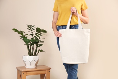 Photo of Woman with eco bag near green plant on color background. Mock up for design