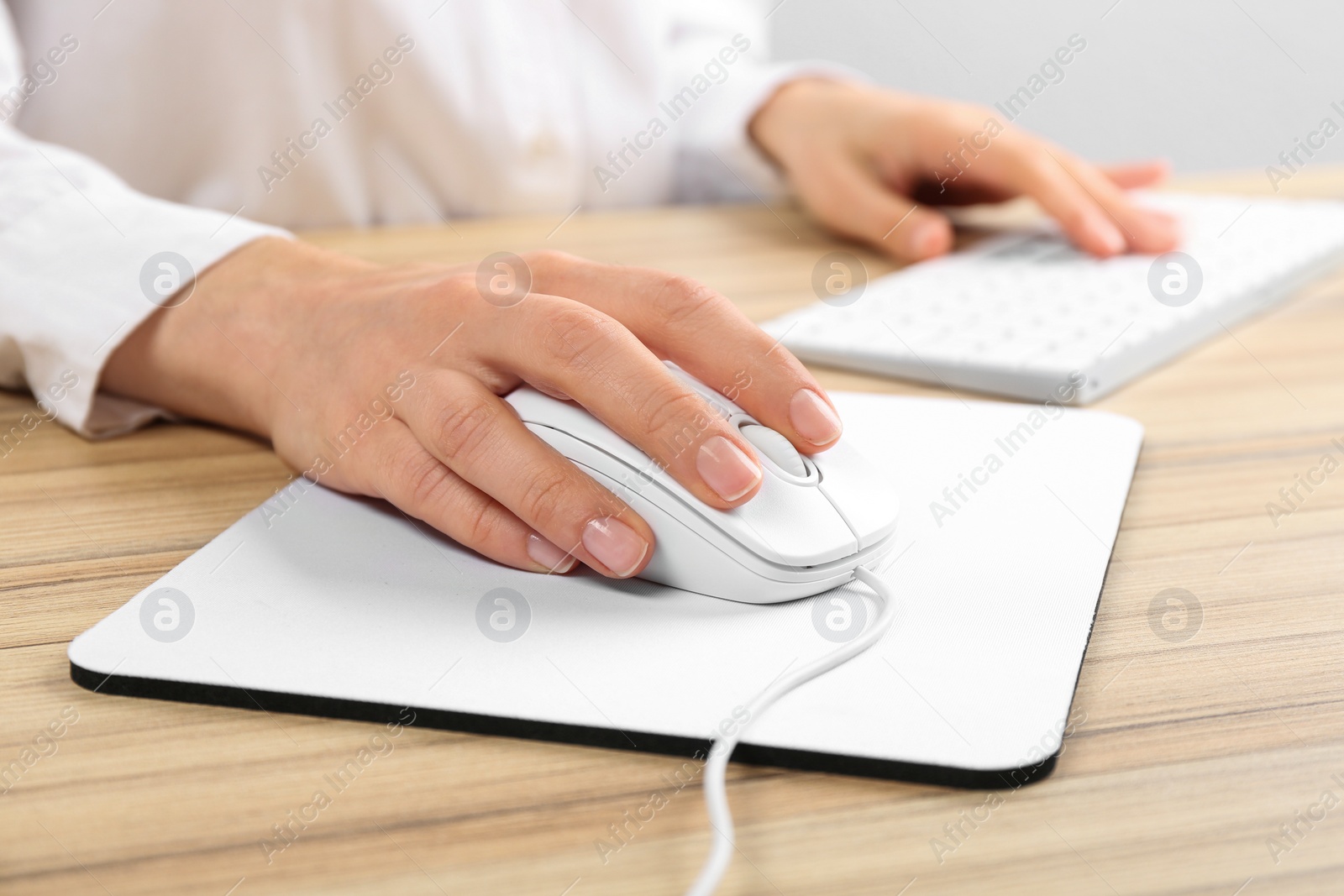 Photo of Woman using modern wired optical mouse at office table, closeup