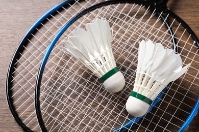 Photo of Feather badminton shuttlecocks and rackets on wooden table, above view