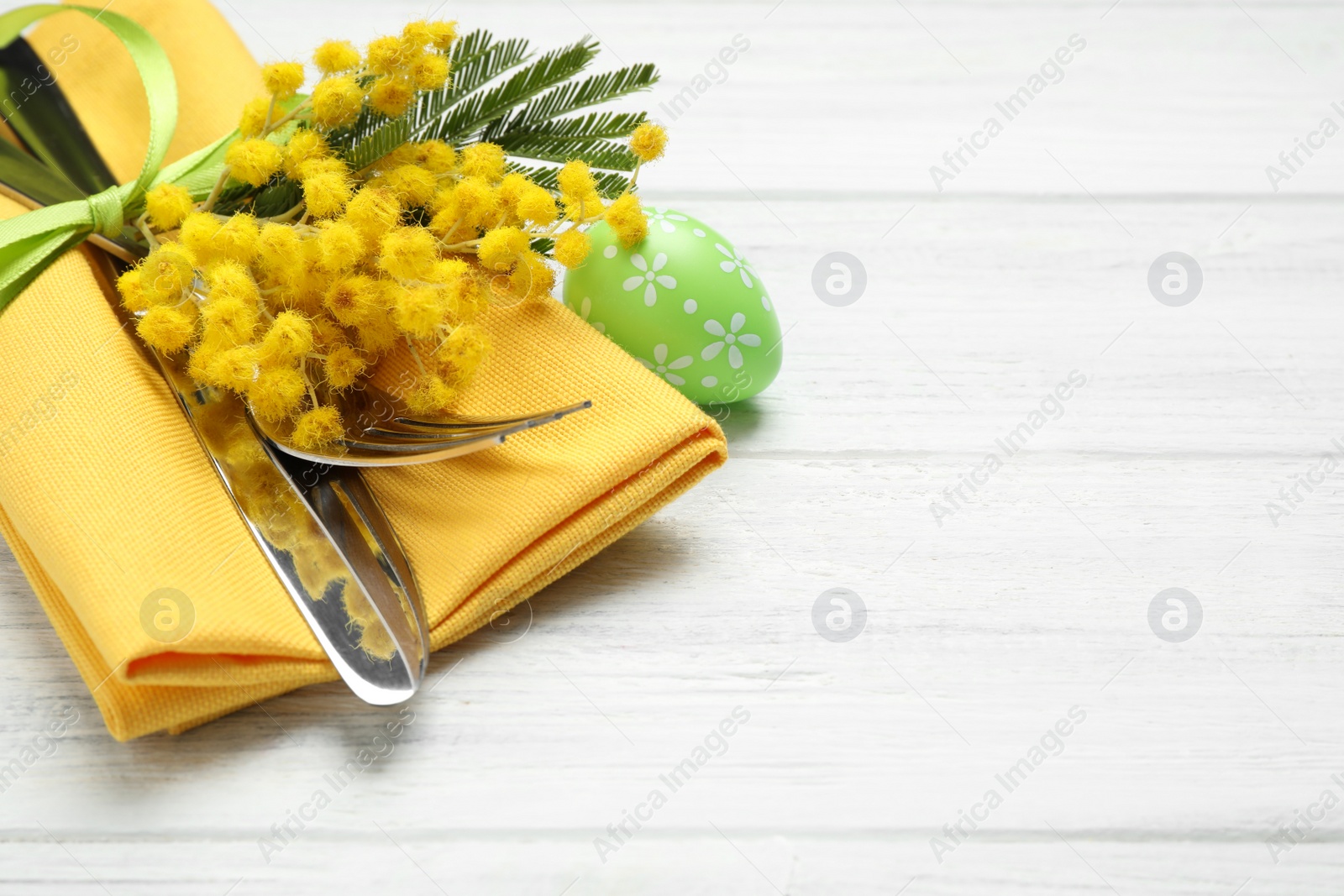 Photo of Closeup view of cutlery set with floral decor on wooden table, space for text. Easter celebration