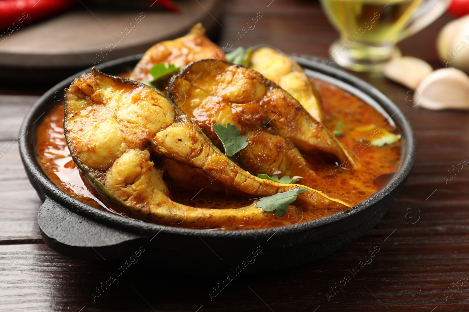 Photo of Tasty fish curry on wooden table, closeup. Indian cuisine