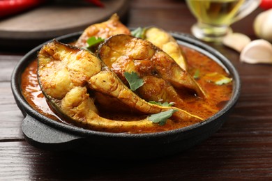 Photo of Tasty fish curry on wooden table, closeup. Indian cuisine