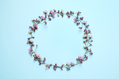 Photo of Frame made of beautiful flowers with space for text on light blue background, top view. Floral card design