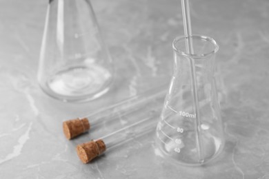 Photo of Different laboratory glassware on grey marble table, closeup