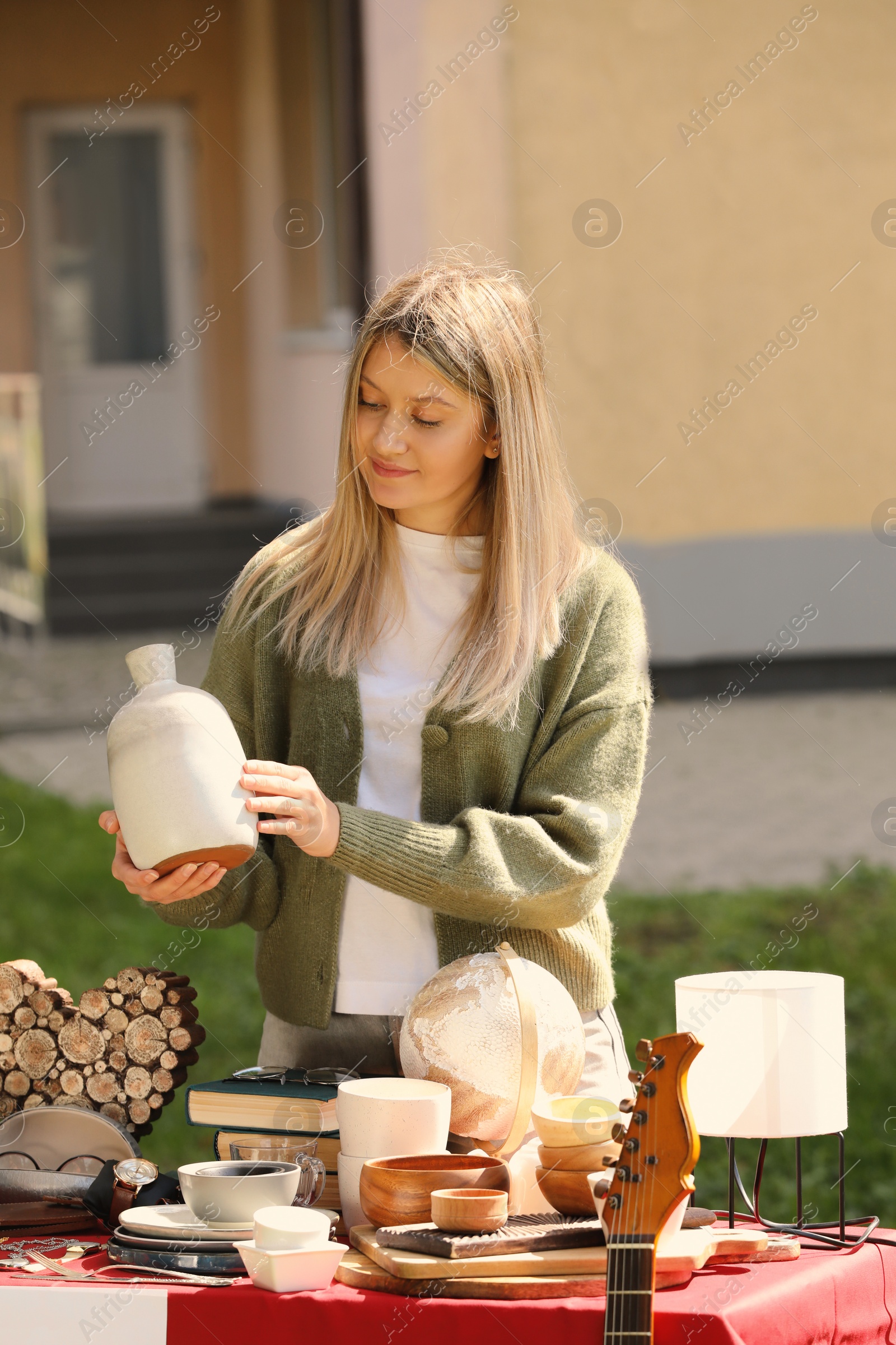 Photo of Woman selling different items on garage sale in yard