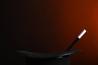 Photo of Magician's hat and wand on dark background, closeup. Space for text