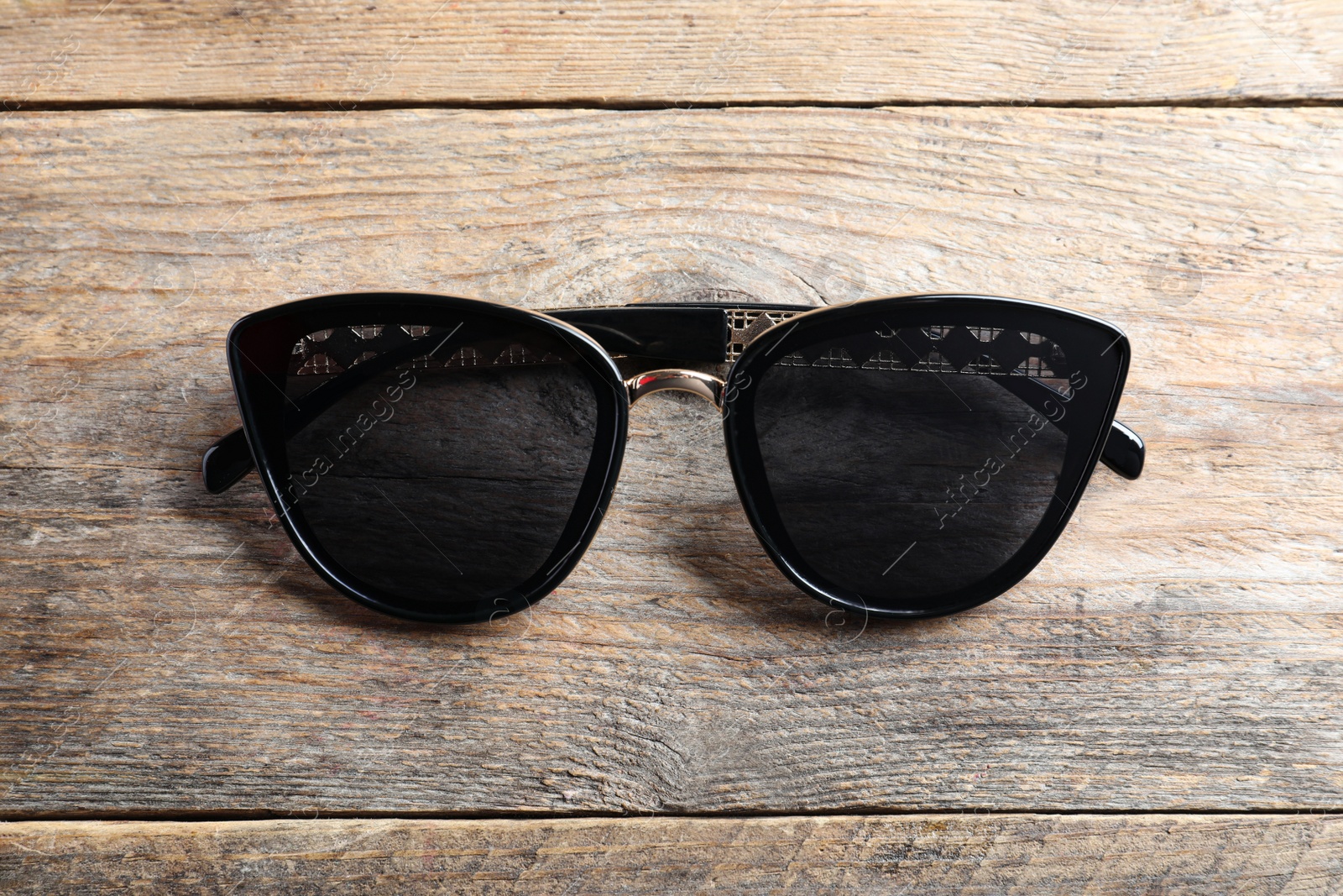 Photo of Stylish sunglasses on wooden background, top view