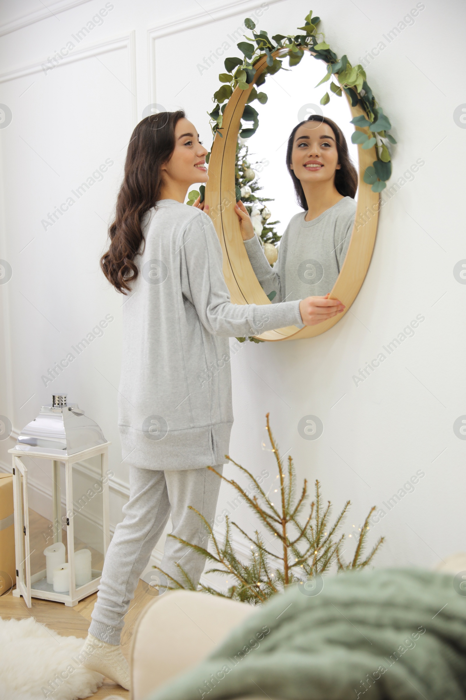 Photo of Woman decorating mirror with eucalyptus branches at home