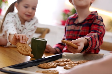 Photo of Little children taking tasty Christmas cookies from baking sheet, closeup