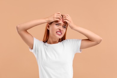 Suffering from allergy. Young woman scratching her face on beige background