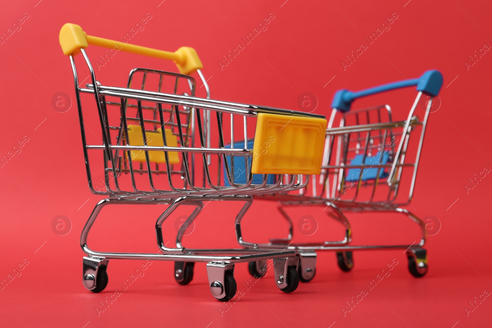 Photo of Empty shopping trolleys on color background, closeup