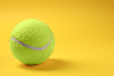 Photo of One tennis ball on yellow background, space for text