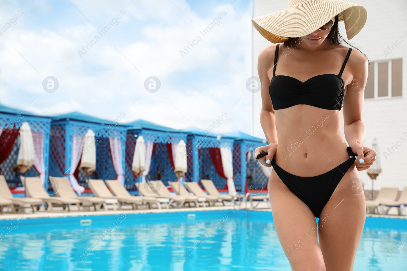 Photo of Young woman in stylish black bikini near swimming pool. Space for text