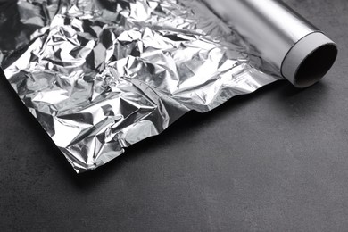 Photo of Roll of aluminum foil on dark grey table, closeup