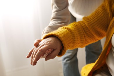 Young and elderly women holding hands together indoors, closeup