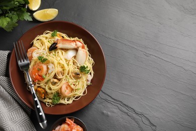 Photo of Delicious pasta with sea food served on black table, flat lay. Space for text