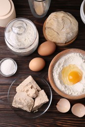 Compressed yeast, salt, flour, dough and eggs on wooden table, flat lay