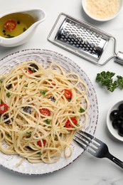 Photo of Delicious pasta with olives, tomatoes and parmesan cheese served on white marble table, flat lay