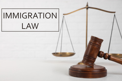 Judge's gavel, scales and words IMMIGRATION LAW on light background