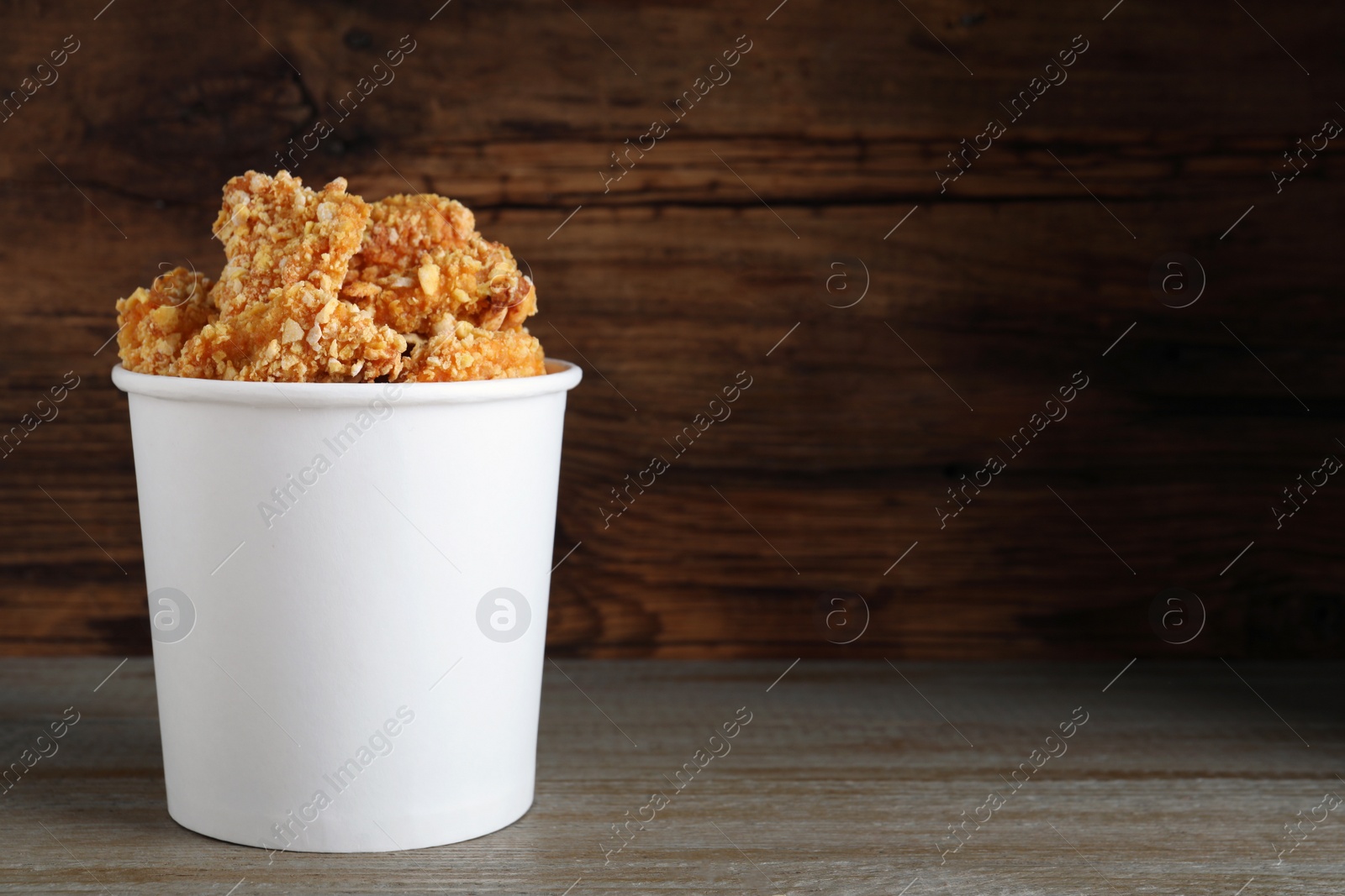 Photo of Bucket with yummy nuggets on table against wooden background, space for text