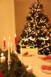 Festive table setting and beautiful Christmas decor in room. Interior design