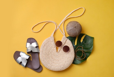 Stylish straw bag and summer accessories on yellow background, flat lay