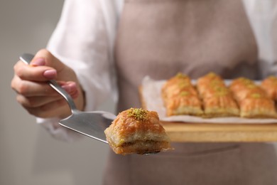 Photo of Woman with delicious sweet baklava on grey background, selective focus