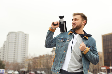 Young man with vintage video camera on city street