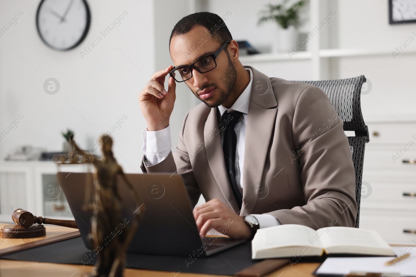 Photo of Serious lawyer working with laptop at table in office