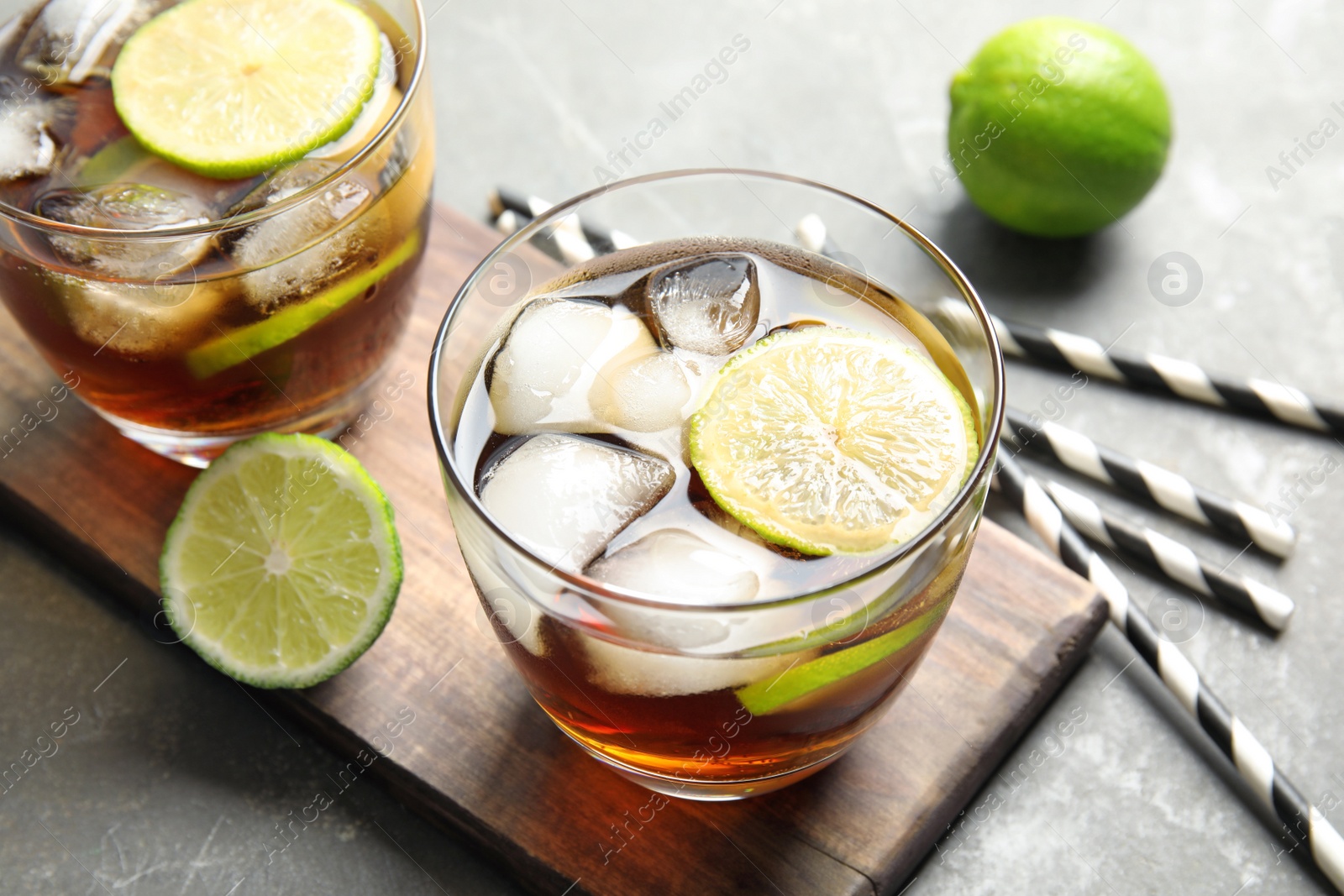 Photo of Glasses of cocktail with cola, ice and cut lime on table
