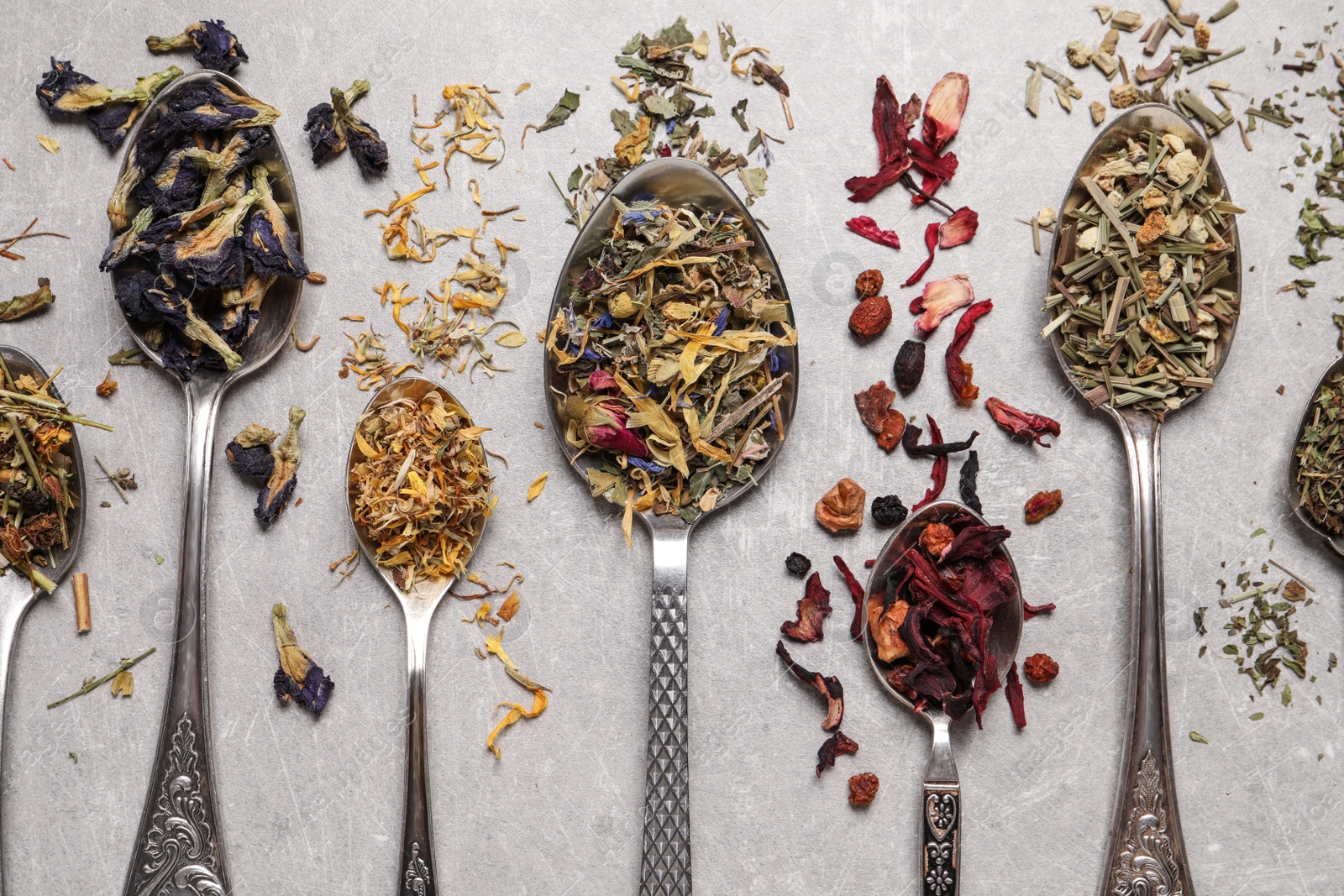 Photo of Flat lay composition with different dry teas and spoons on light table