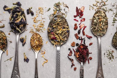 Photo of Flat lay composition with different dry teas and spoons on light table
