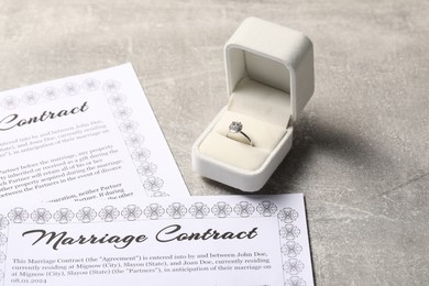 Photo of Marriage contract and ring with gemstone on grey table
