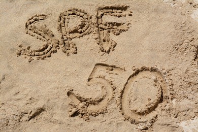 Photo of Abbreviation SPF 50 written on sand at beach