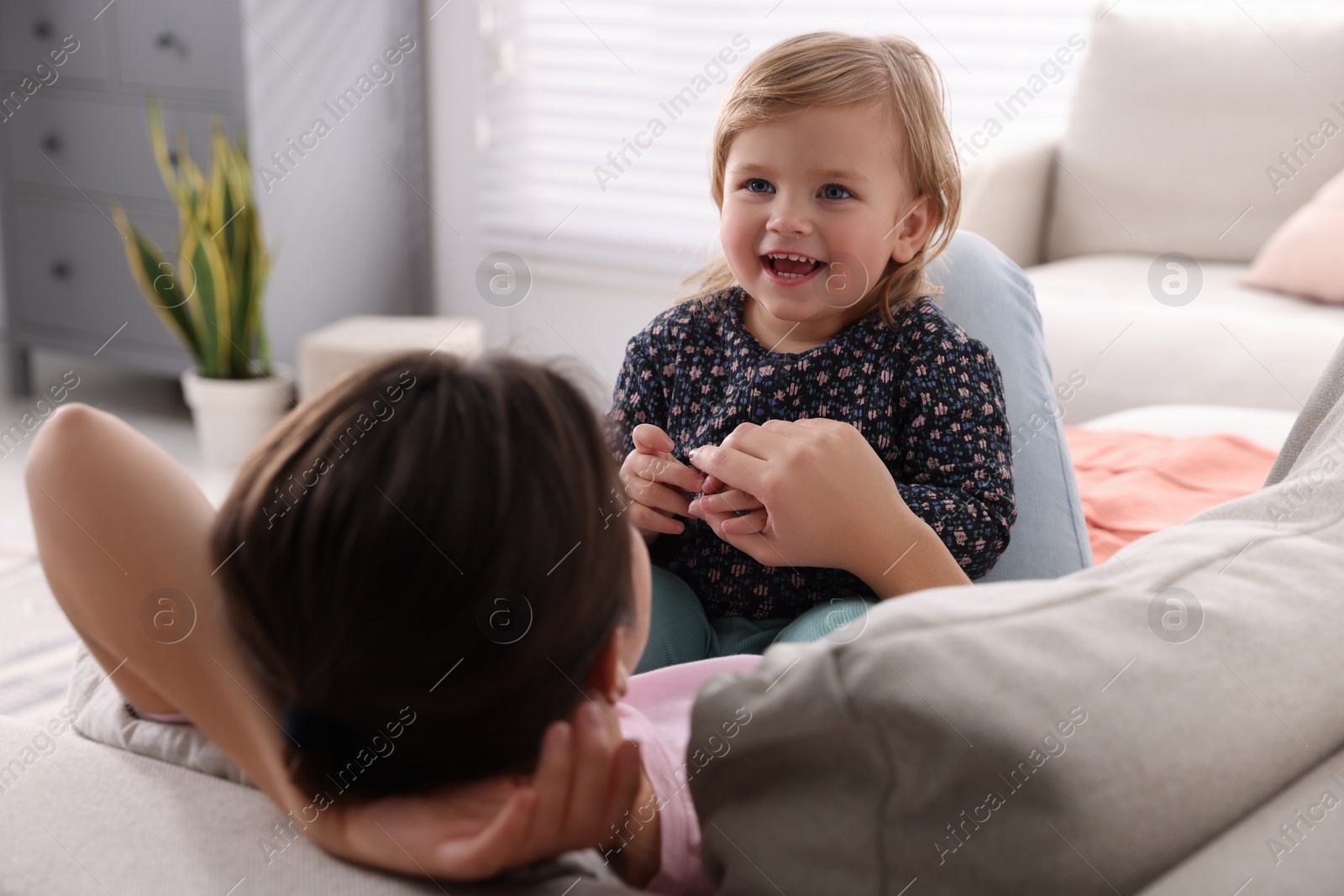 Photo of Mother with her cute little daughter on sofa at home