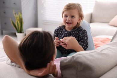 Mother with her cute little daughter on sofa at home