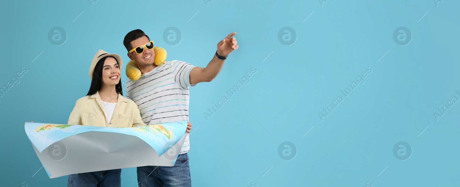 Photo of Couple of tourists with map on light blue background