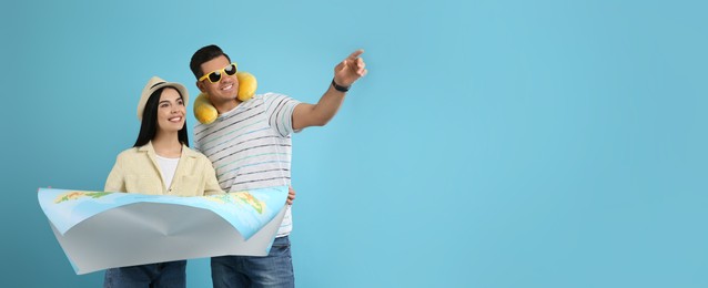 Couple of tourists with map on light blue background