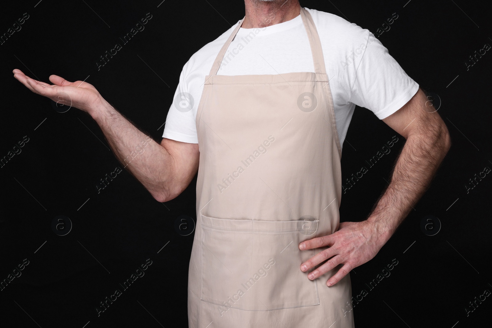 Photo of Man wearing kitchen apron on black background, closeup. Mockup for design