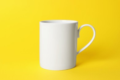 Photo of One white ceramic mug on yellow background