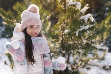 Cute little girl with snowballs outdoors on winter day. Christmas vacation